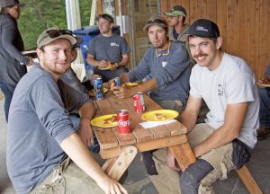 Collyers Construction workers sit at a picnic table enjoying pizza.